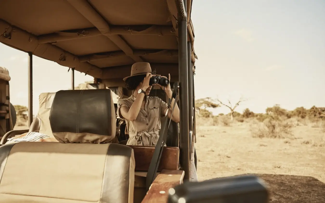 Guest photographing wildlife from open safari vehicle, Tawi Lodge, Amboseli and Chyulu Hills, Kenya
