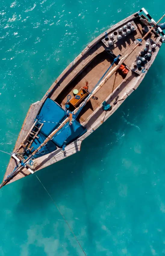 Fishing boat anchored in turquoise shallow water, aerial view, Mafia Archipelago, Tanzania