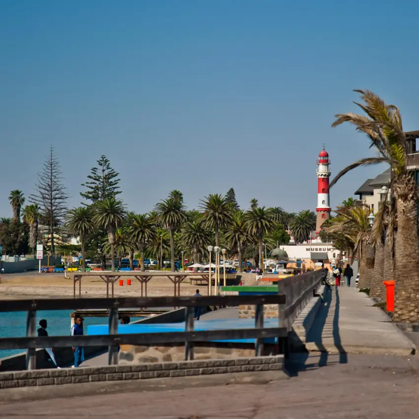 Beachfront promenade with palm trees and red lighthouse, Swakopmund, Namibia