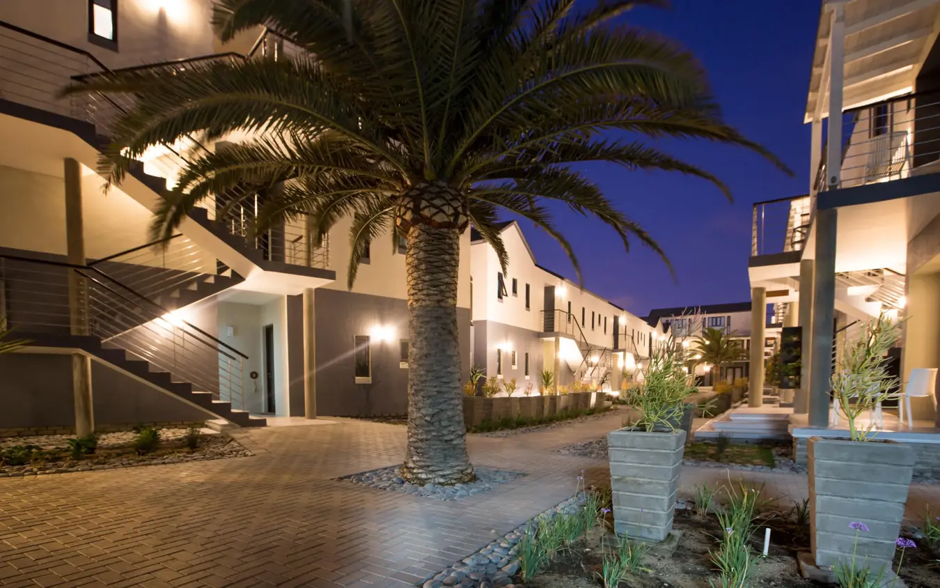 Modern lodge courtyard with palm tree at twilight, The Delight Swakopmund, Swakopmund, Namibia