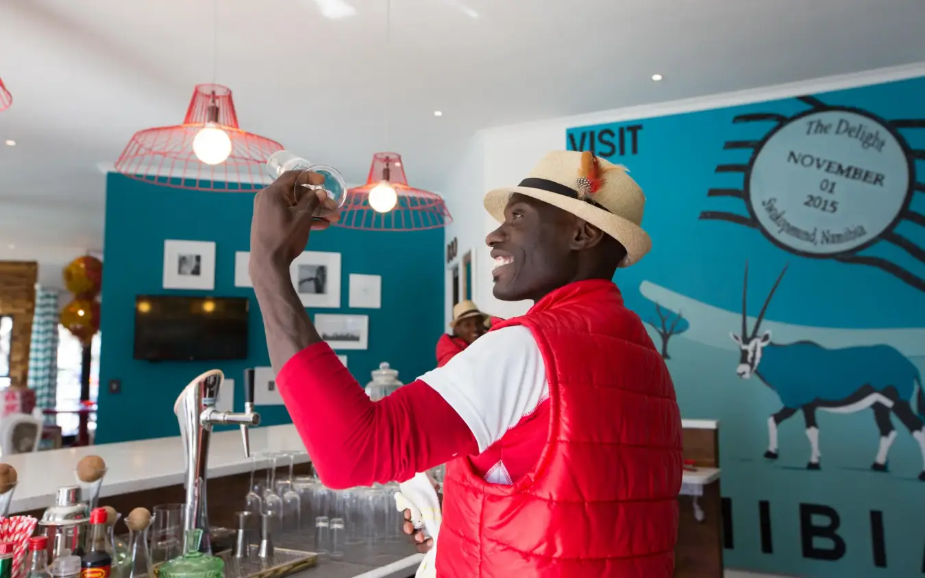 Man in red jacket examining pendant light fixture indoors, The Delight Swakopmund, Swakopmund, Namibia