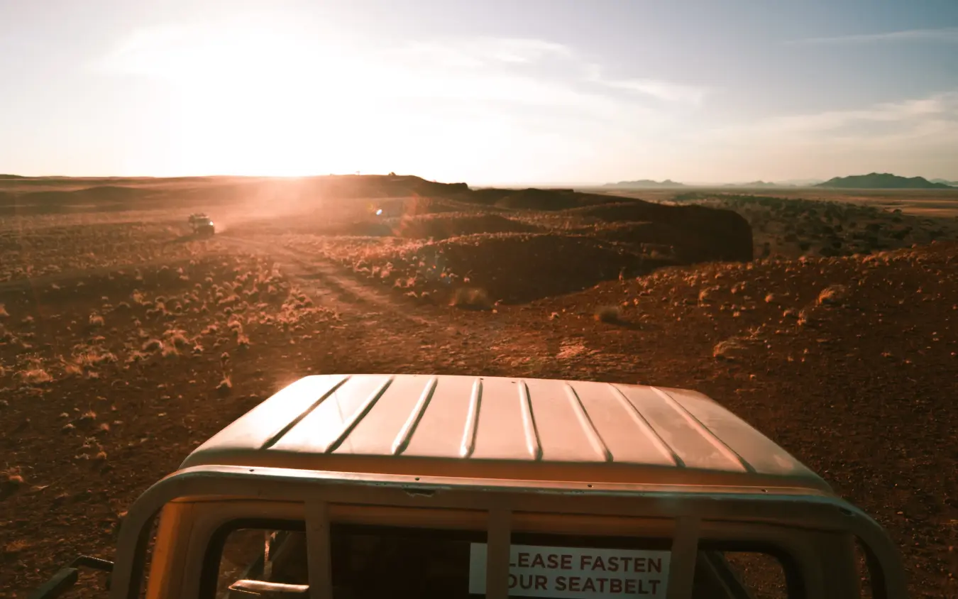 Roof of safari vehicle with vast arid landscape at sunset, The Desert Grace, Sossusvlei, Namibia