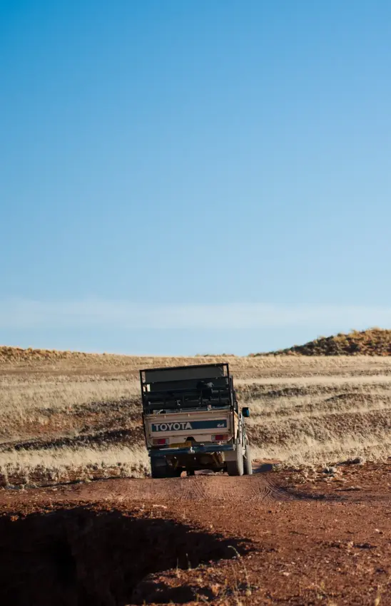 Toyota truck parked on dirt road through arid agricultural landscape, The Desert Grace, Sossusvlei, Namibia