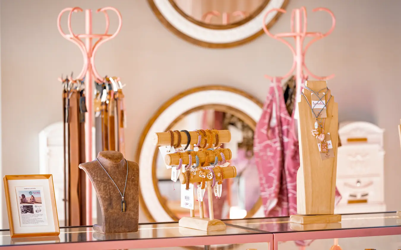 Jewelry display with wooden stands and neon pink coat racks in boutique, The Desert Grace, Sossusvlei, Namibia