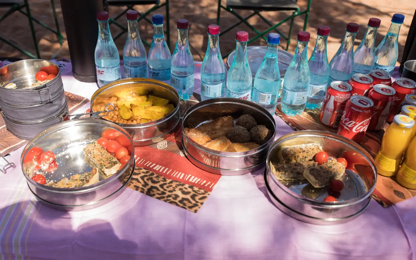 Outdoor dining setup with multiple dishes and beverages on purple tablecloth, The Desert Grace, Sossusvlei, Namibia