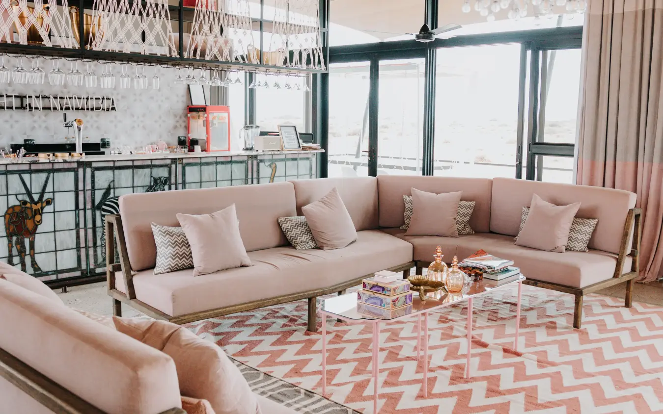Modern lounge with pink sectional sofa overlooking landscape through floor-to-ceiling windows, The Desert Grace, Sossusvlei, Namibia