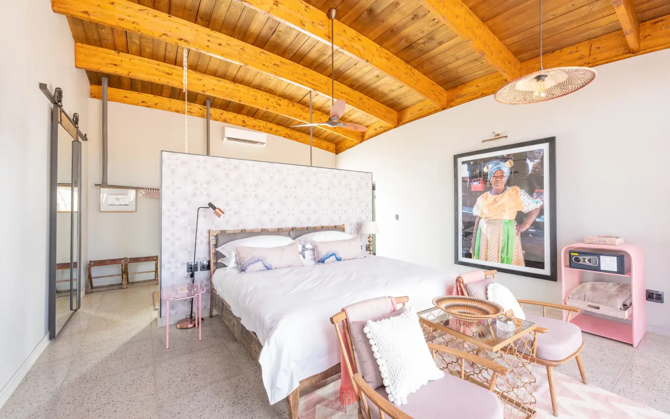 Modern bedroom with exposed wooden beams and pink accent furniture, The Desert Grace, Sossusvlei, Namibia