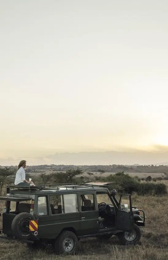 Guest on safari vehicle roof at golden hour sunset, The Emakoko, Nairobi, Kenya