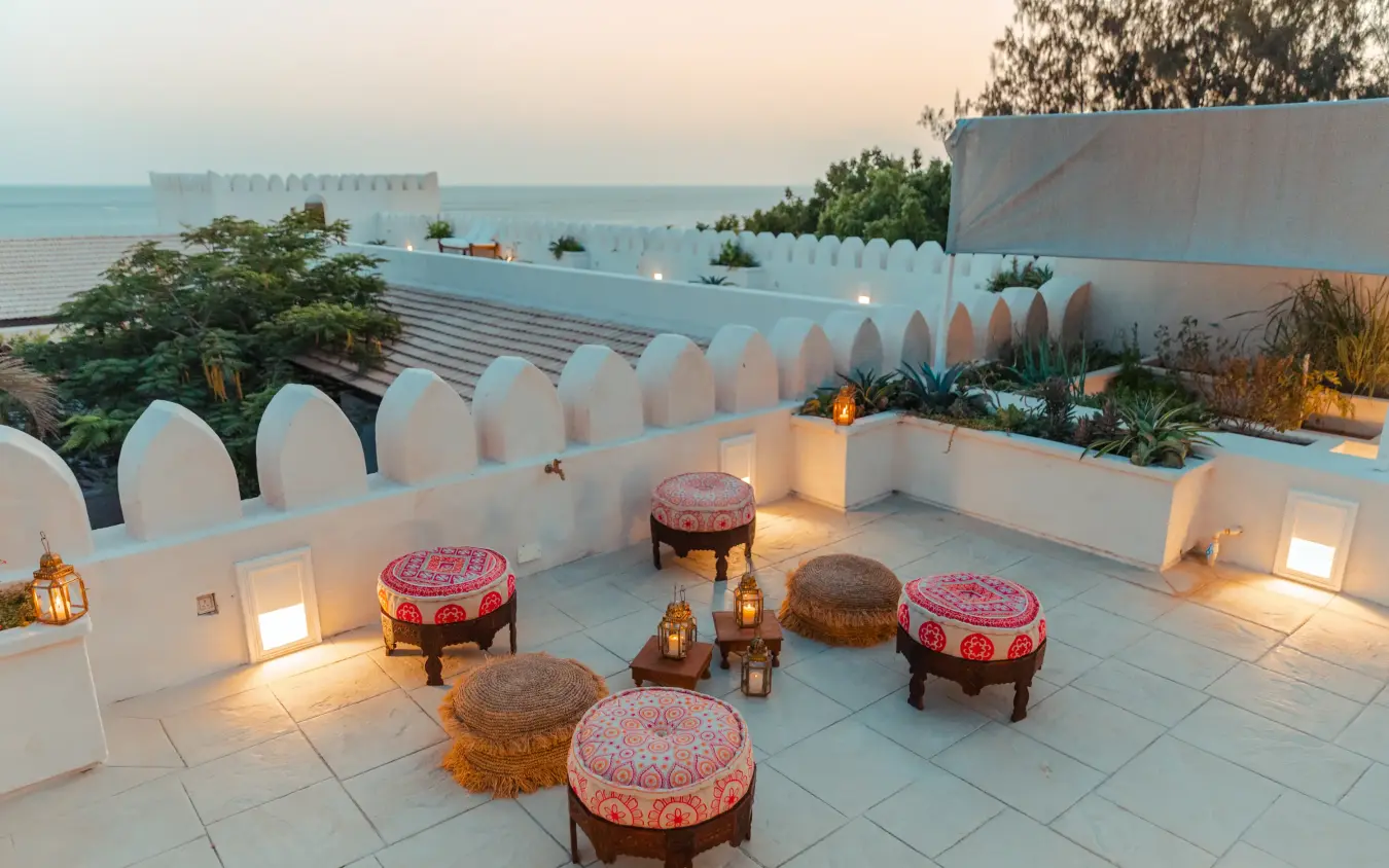 Rooftop terrace with cushioned seating overlooking ocean at dusk, The Fort, Lamu Archipelago, Kenya