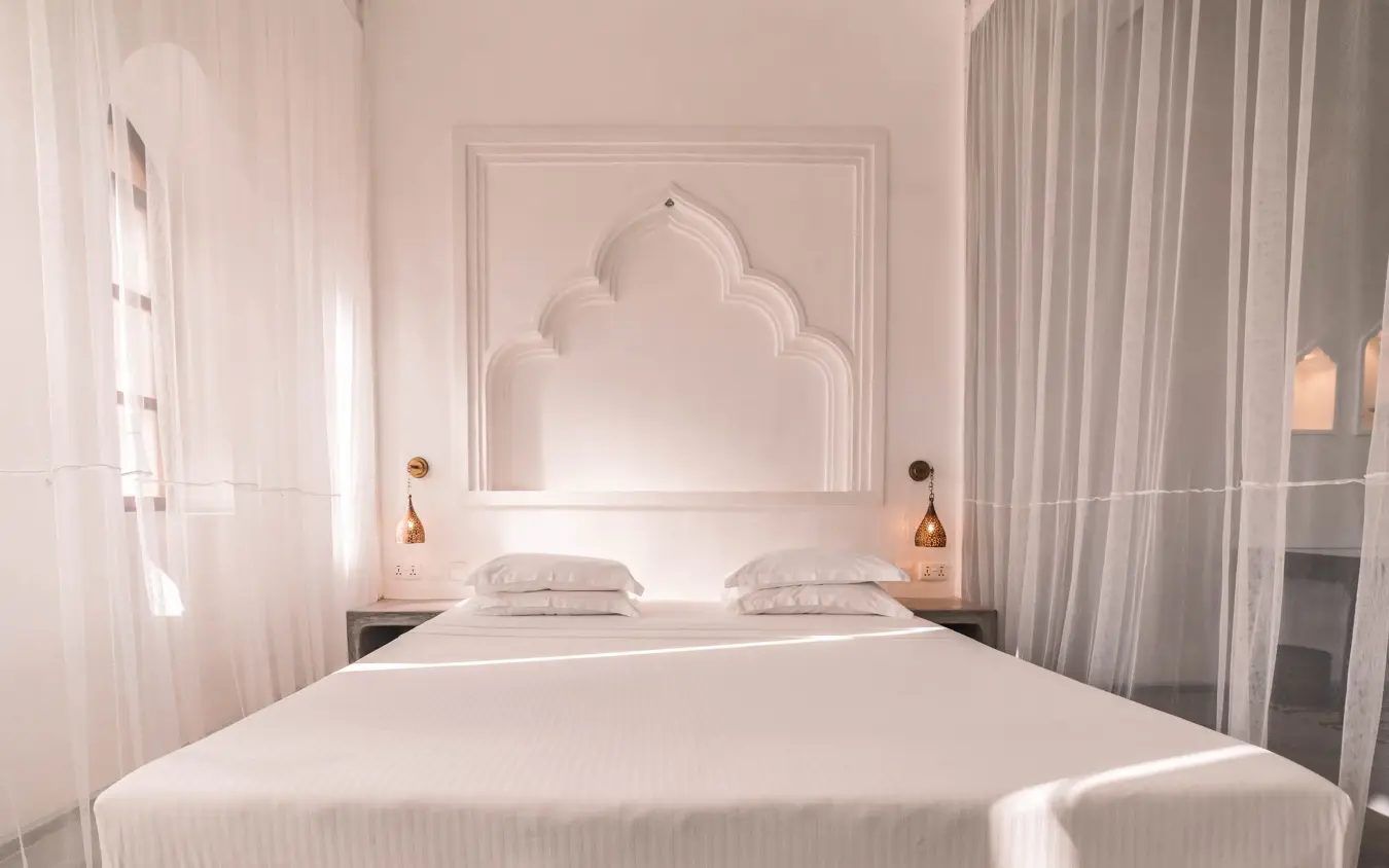 Luxury bedroom with ornate headboard and sheer curtains, The Fort, Lamu Archipelago, Kenya