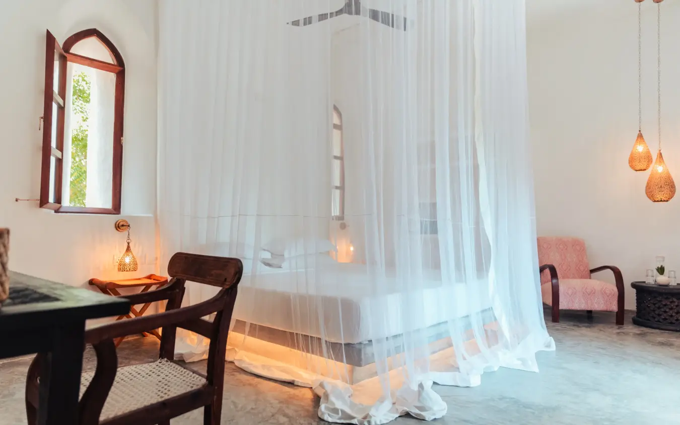 Bedroom with sheer canopy, pendant lights, and arched window, The Fort, Lamu Archipelago, Kenya