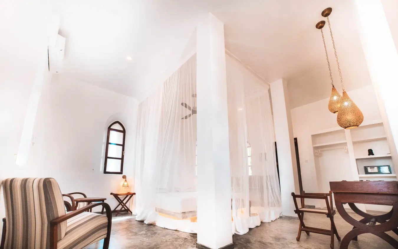 Spacious bedroom with sheer curtains and wooden furniture, The Fort, Lamu Archipelago, Kenya