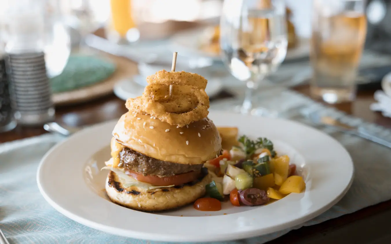 Gourmet burger with onion ring on fine dining plate at table setting, The Hide, Hwange National Park, Zimbabwe