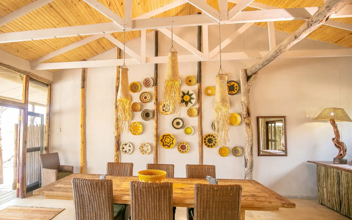 Dining room with wooden table and decorative plates on whitewashed walls, The Hide, Hwange National Park, Zimbabwe