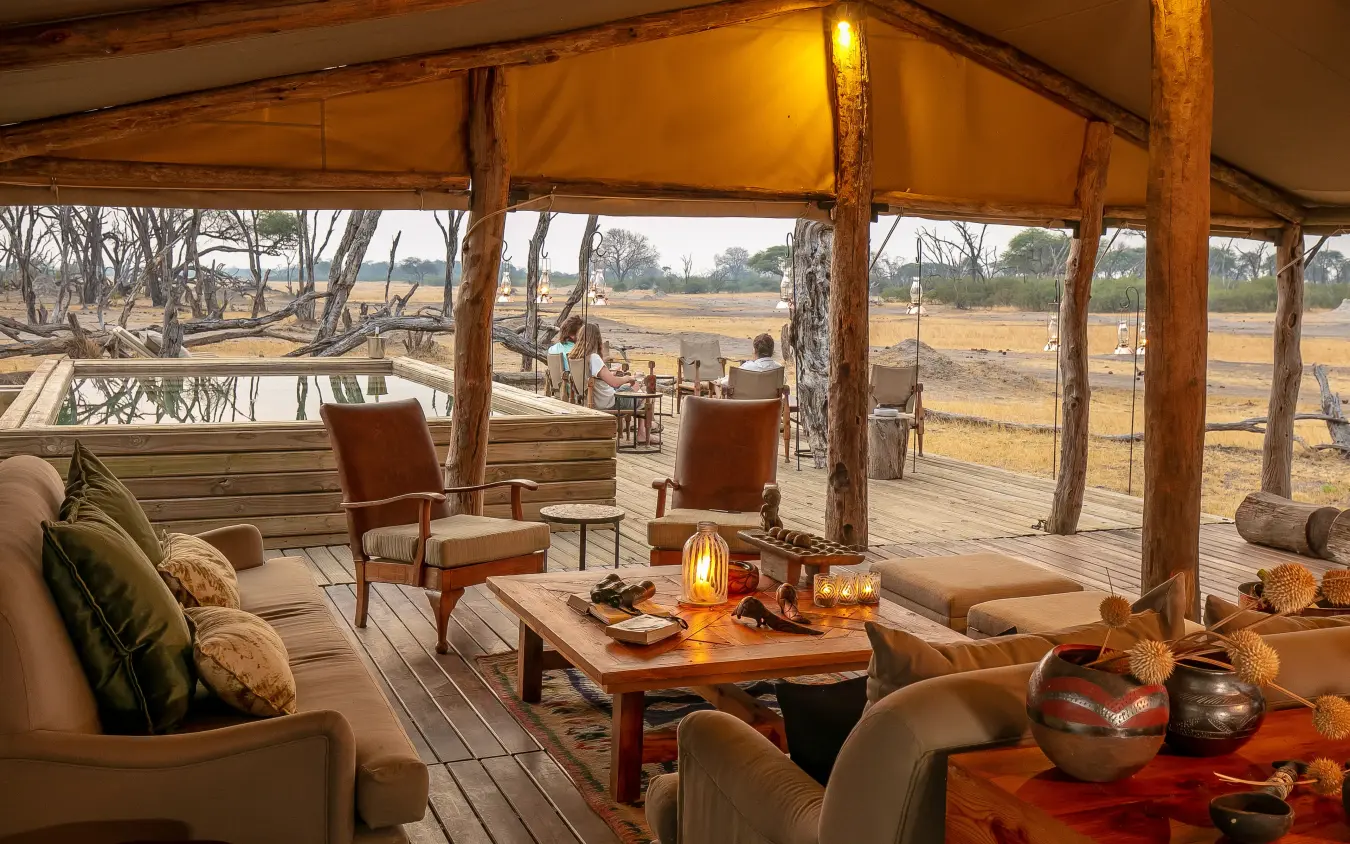 Open-air lodge pavilion with seating overlooking vast savanna landscape at dusk, The Hide, Hwange National Park, Zimbabwe