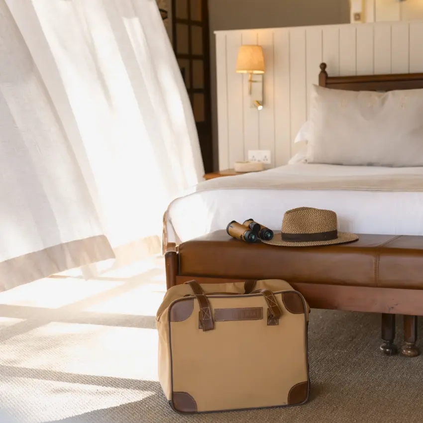 Bedroom with packed luggage and safari hat on leather bench, The Hide, Hwange National Park, Zimbabwe