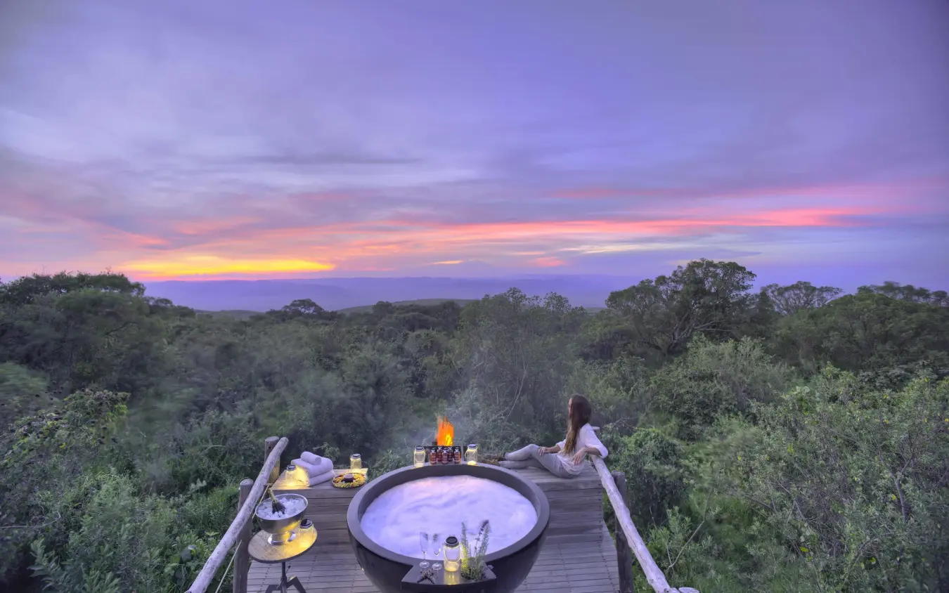 Elevated wooden deck with hot tub overlooking forest at sunset, The Highlands, Ngorongoro Crater, Tanzania