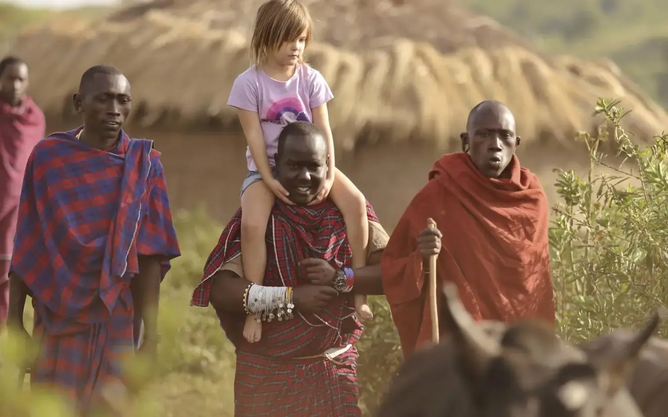 Child riding on local guide's shoulders during village walk, The Highlands, Ngorongoro Crater, Tanzania