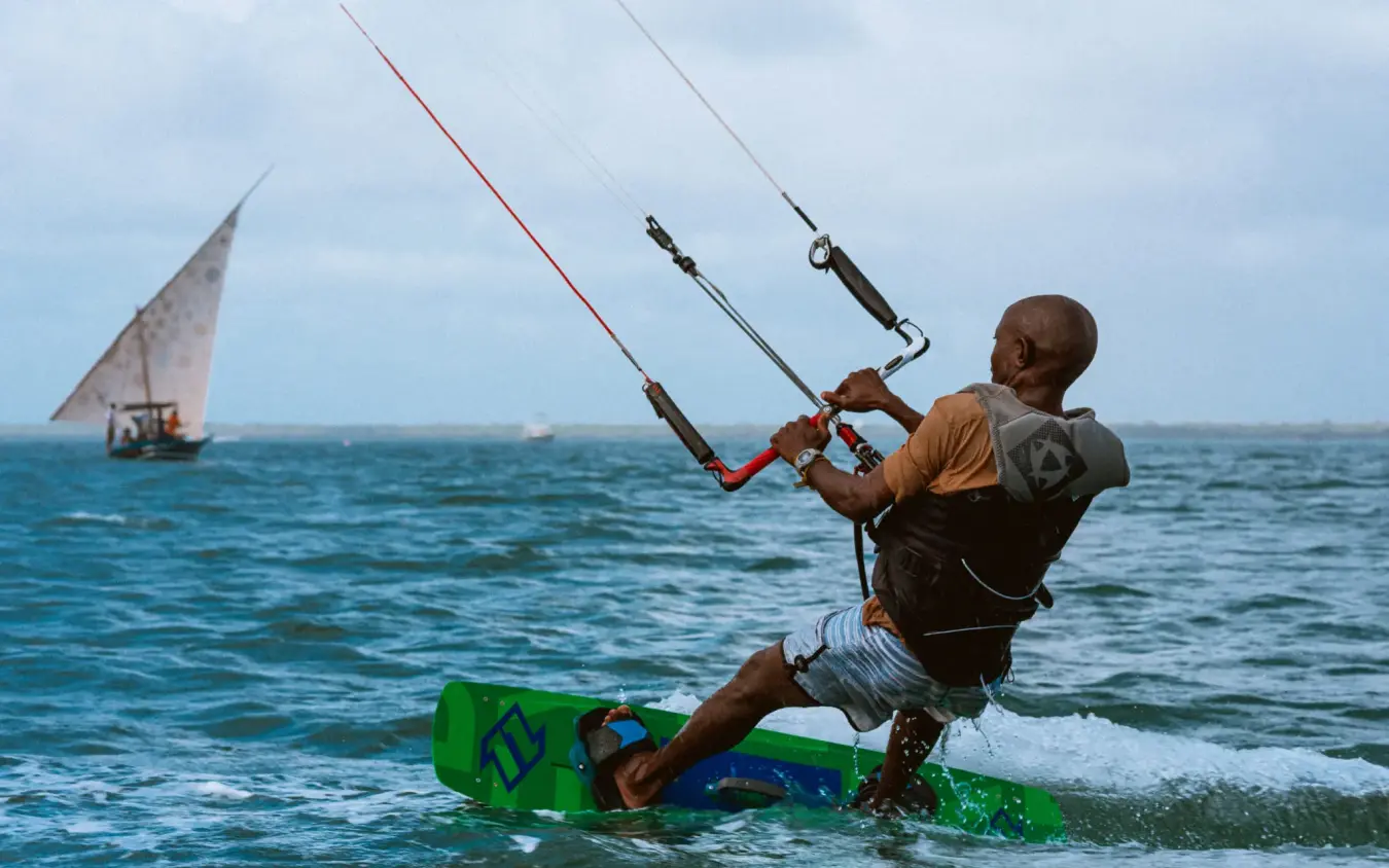 Man kitesurfing in ocean with traditional sailing dhow, The Majlis Resort, Lamu Archipelago, Kenya