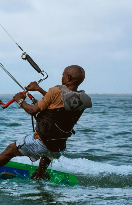 Man kitesurfing in ocean with traditional sailing dhow, The Majlis Resort, Lamu Archipelago, Kenya