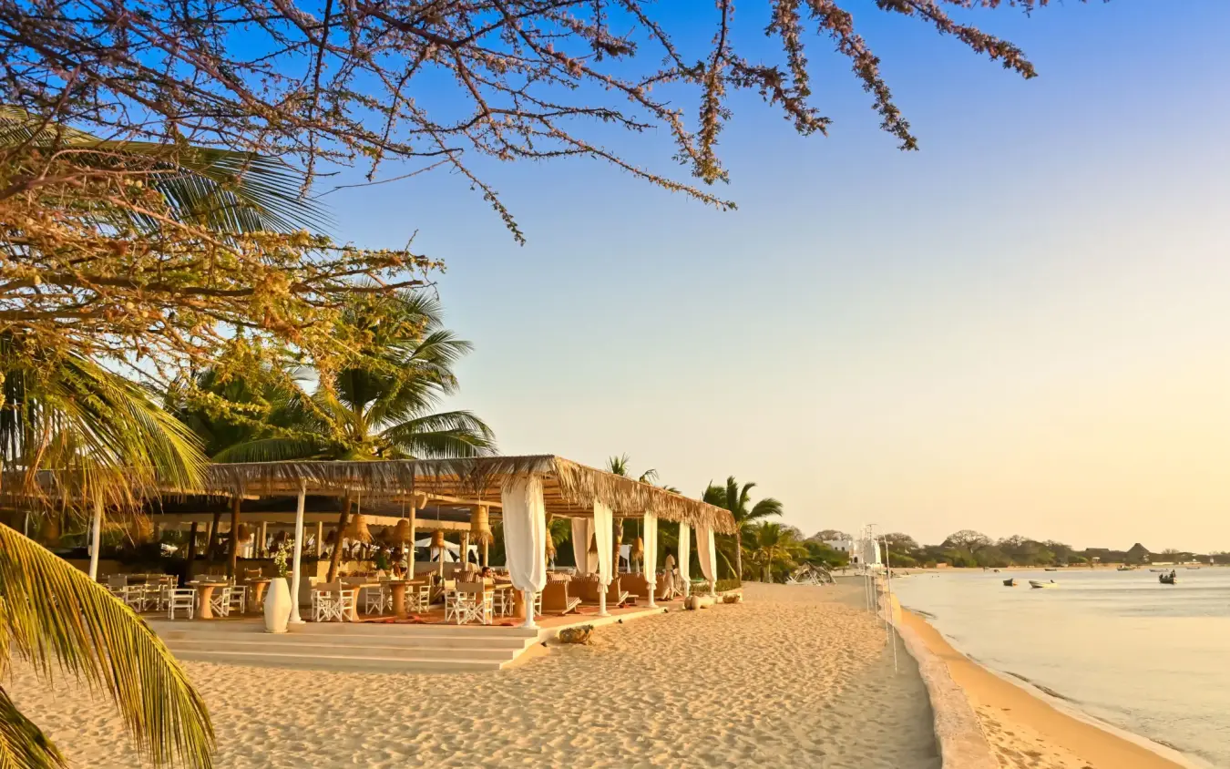 Beach lodge with thatched structures and waterfront at sunset, The Majlis Resort, Lamu Archipelago, Kenya
