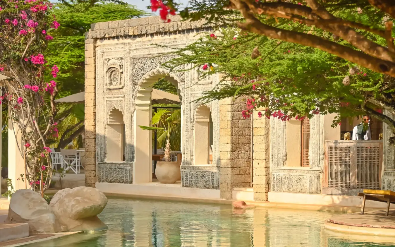 Stone architecture with arched doorways beside reflecting pool, The Majlis Resort, Lamu Archipelago, Kenya