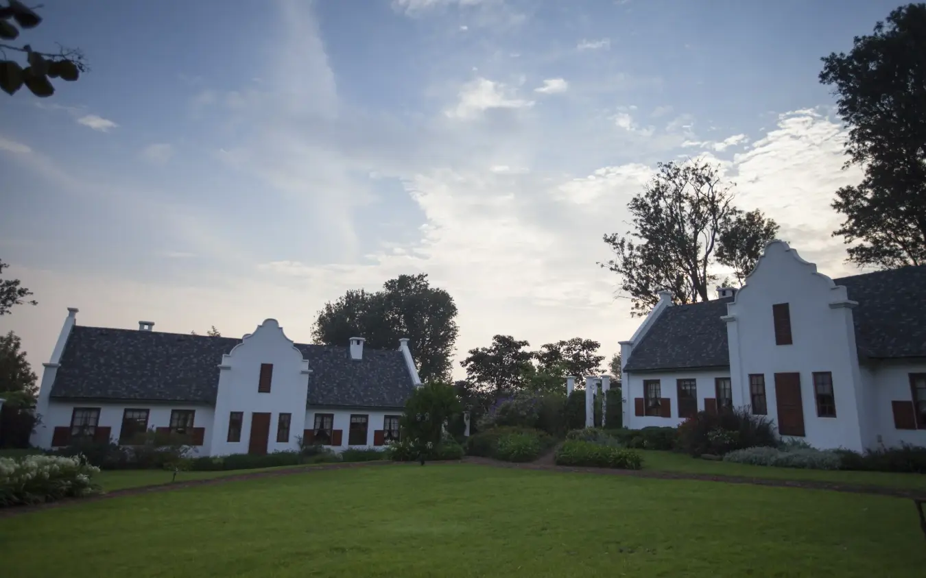 Colonial-style white farmhouses with manicured lawn and shade trees, The Manor at Ngorongoro, Ngorongoro Crater, Tanzania