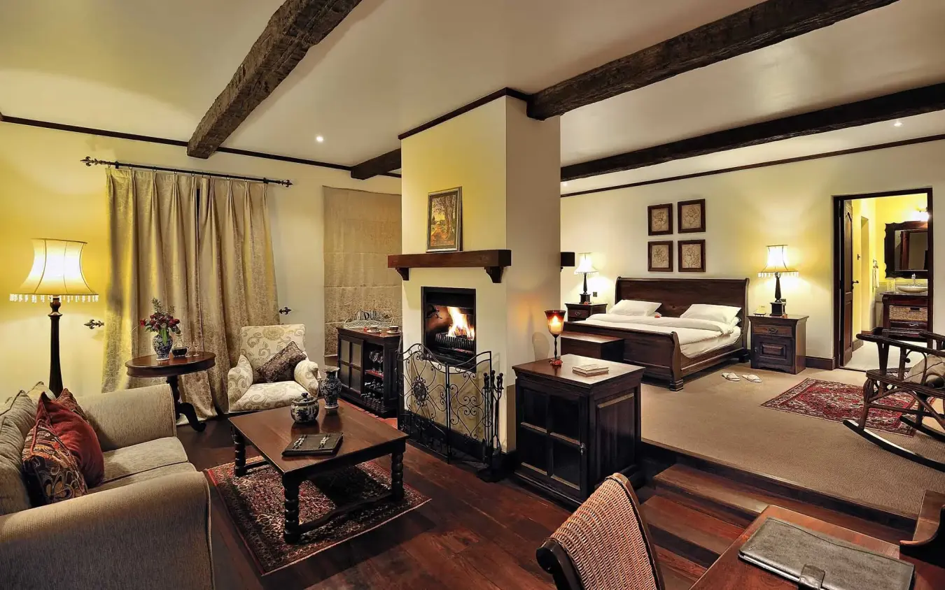 Luxury bedroom suite with fireplace and lounge seating area, The Manor at Ngorongoro, Ngorongoro Crater, Tanzania