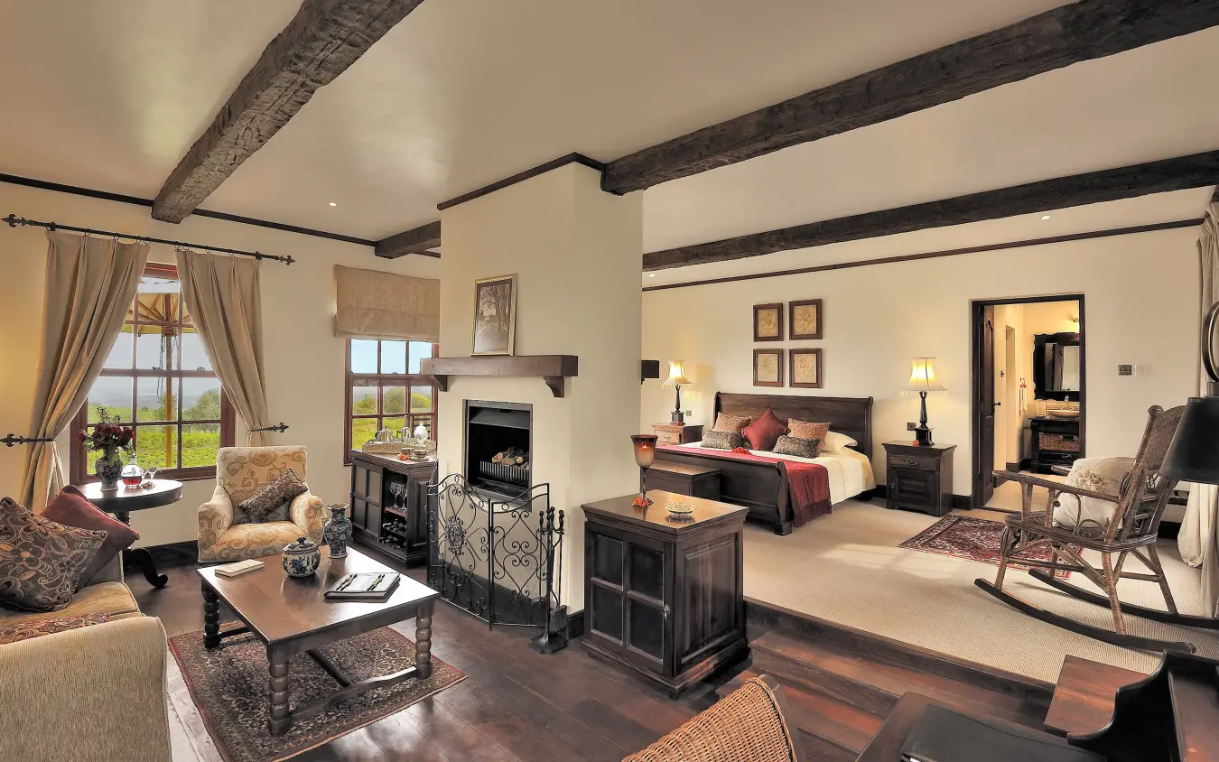 Luxury suite with exposed beams, fireplace and bedroom with countryside views, The Manor at Ngorongoro, Ngorongoro Crater, Tanzania