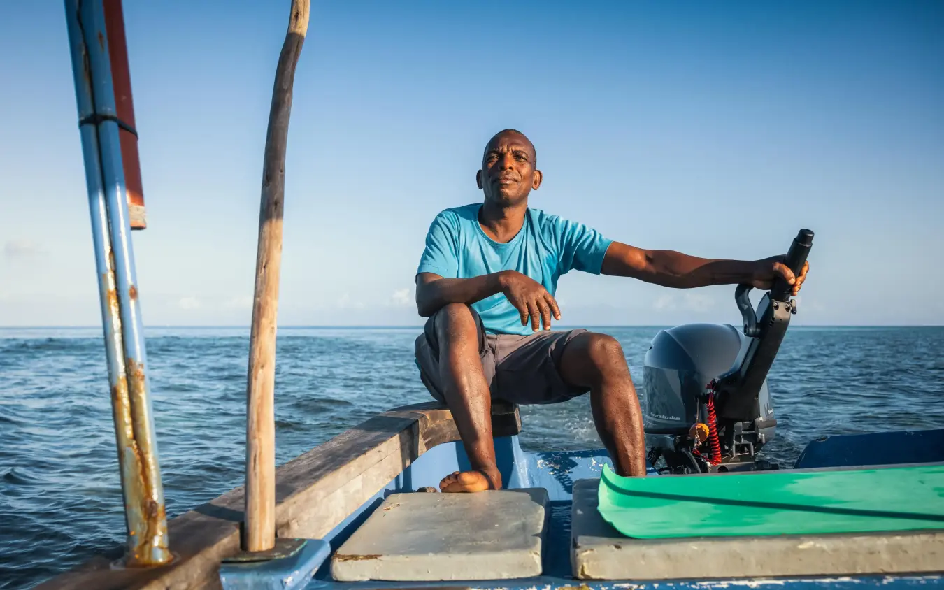 Man sitting in wooden boat on ocean with equipment, The Manta Resort, Zanzibar & Pemba, Tanzania