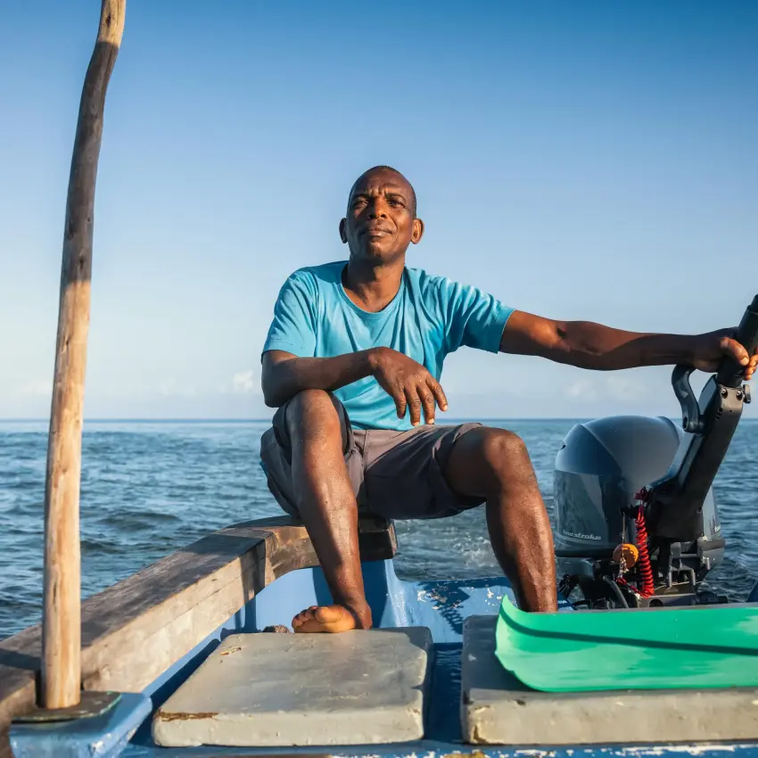 Man sitting in wooden boat on ocean with equipment, The Manta Resort, Zanzibar & Pemba, Tanzania