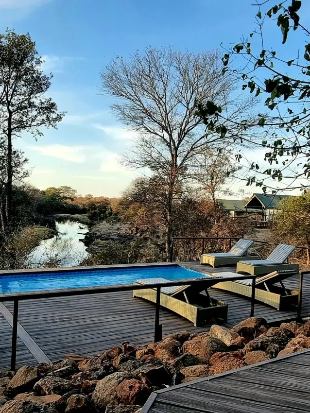 Wooden deck overlooking river with blue table and chairs, The Wallow Lodge, Hwange National Park, Zimbabwe