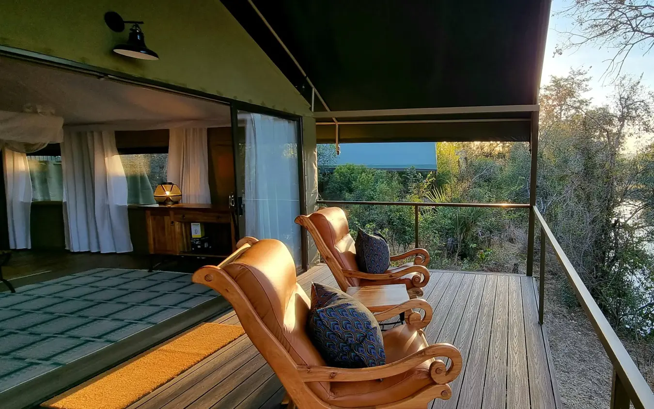 Wooden deck with chairs overlooking river and trees, The Wallow Lodge, Hwange National Park, Zimbabwe