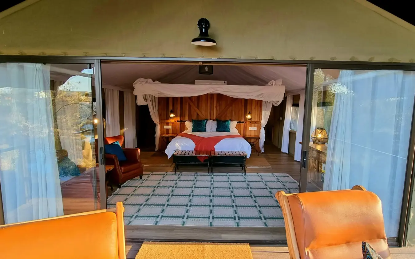 Bedroom interior with double bed viewed from deck, The Wallow Lodge, Hwange National Park, Zimbabwe