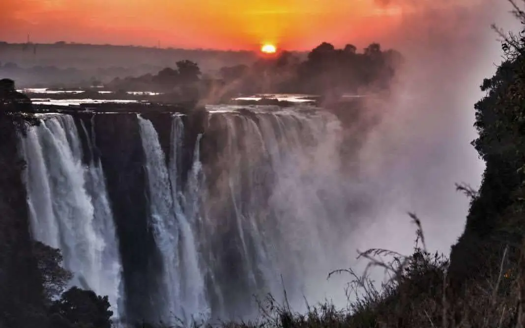Waterfall cascading at sunrise with mist and vegetation, The Wallow Lodge, Hwange National Park, Zimbabwe
