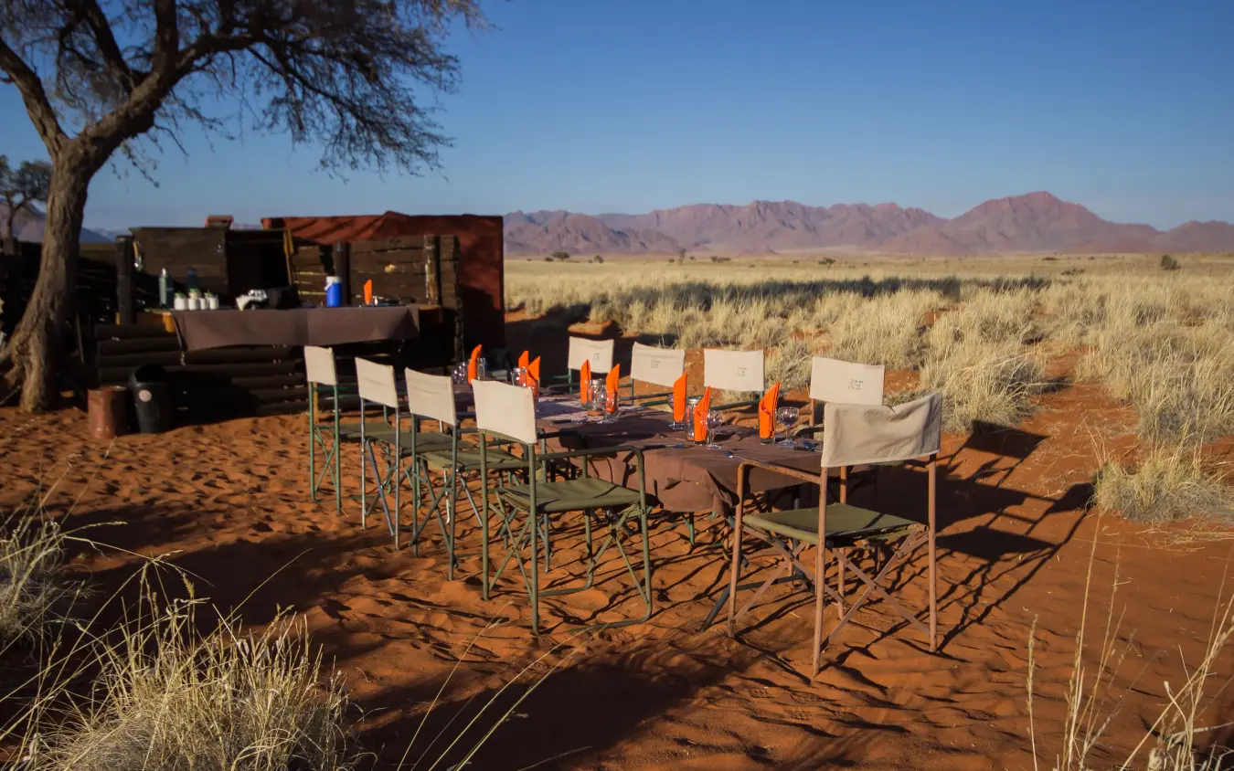 Outdoor dining setup in desert landscape with mountains, Tok Tokkie Trails, NamibRand Private Reserve, Namibia