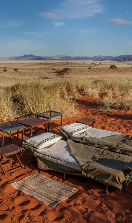 Desert camp setup with sleeping cots and tables in arid landscape, Tok Tokkie Trails, NamibRand Private Reserve, Namibia