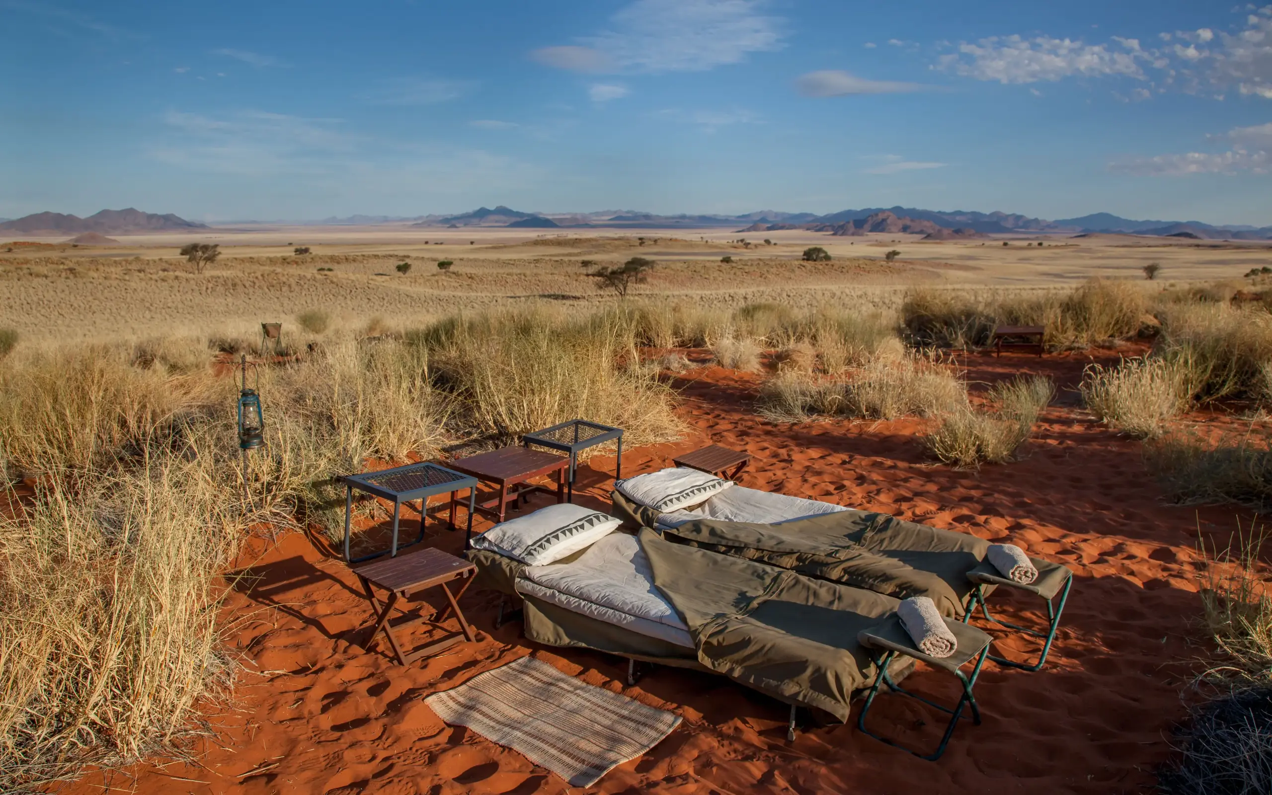 Desert camp setup with sleeping cots and tables in arid landscape, Tok Tokkie Trails, NamibRand Private Reserve, Namibia