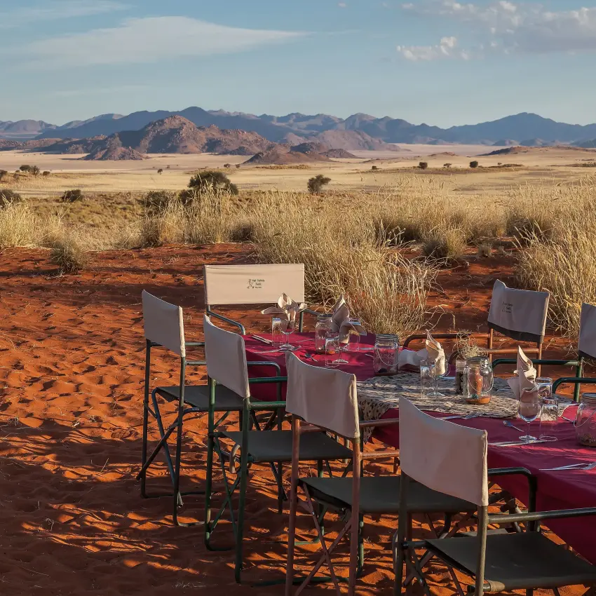 Outdoor dining table set in desert landscape with mountains, Tok Tokkie Trails, NamibRand Private Reserve, Namibia