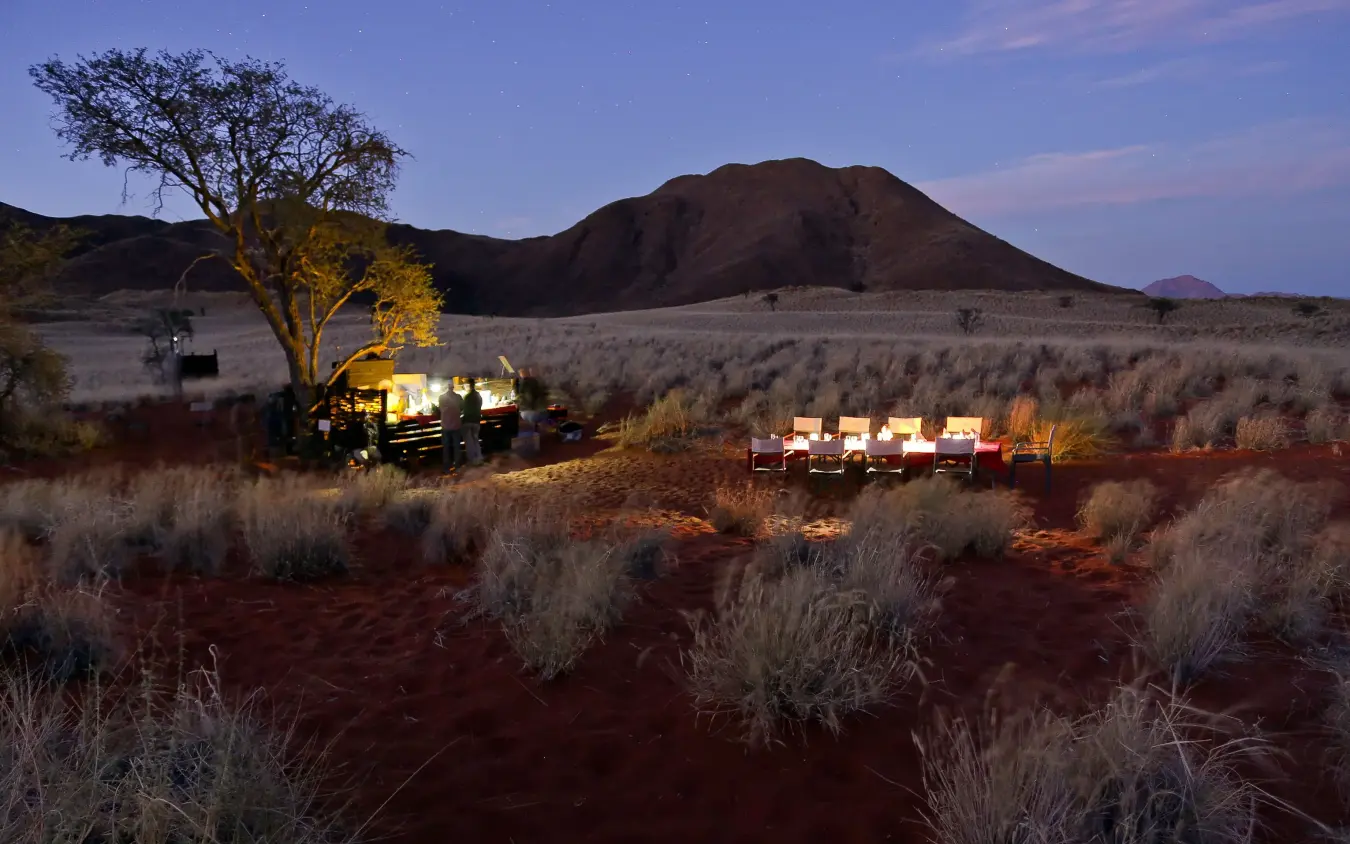 Illuminated safari camp tents under twilight sky with mountain backdrop, Tok Tokkie Trails, NamibRand Private Reserve, Namibia