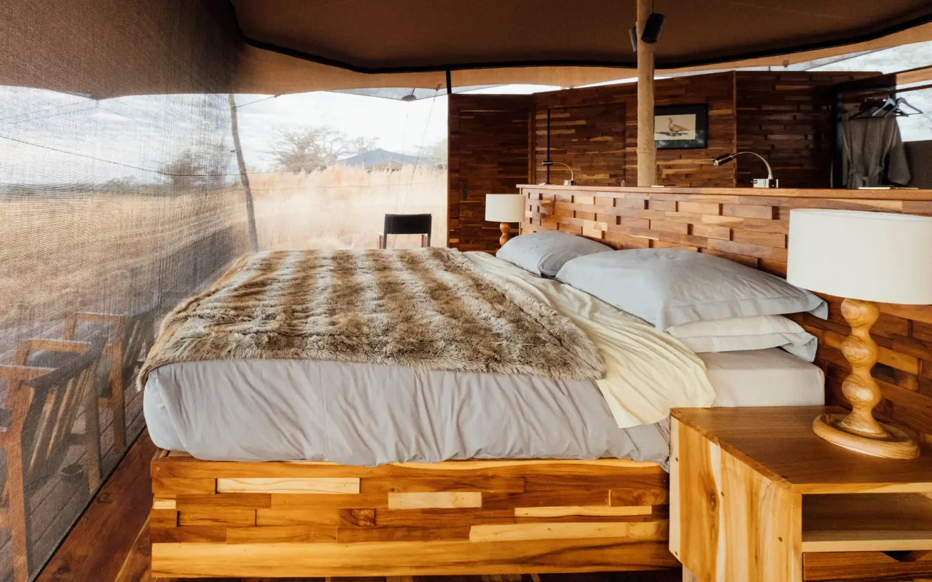 Wooden bed with patterned blanket in safari tent bedroom, Usangu Expedition Camp, Ruaha National Park, Tanzania