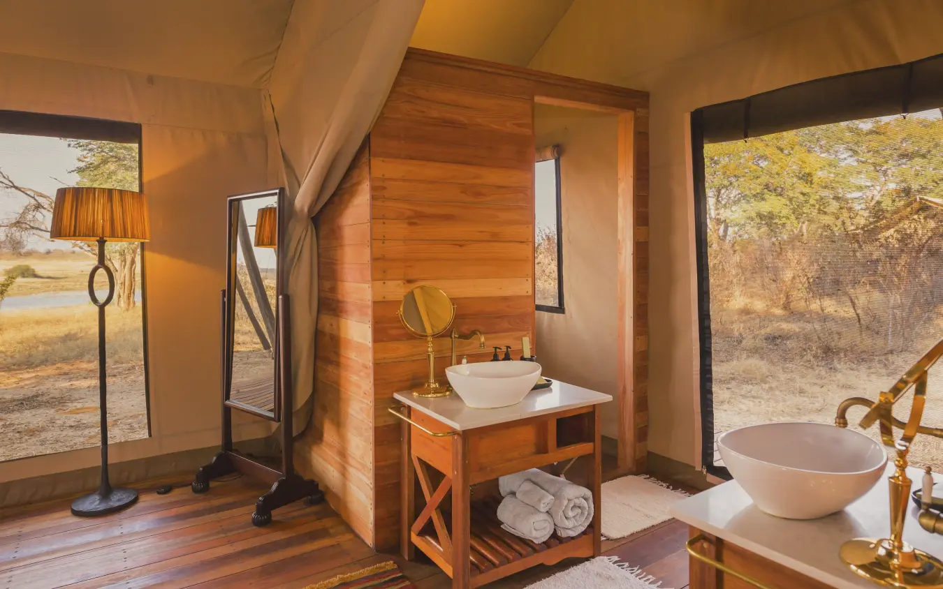 Luxury safari tent bathroom with freestanding bathtub and wooden interior, Verney’s Camp, Hwange National Park, Zimbabwe