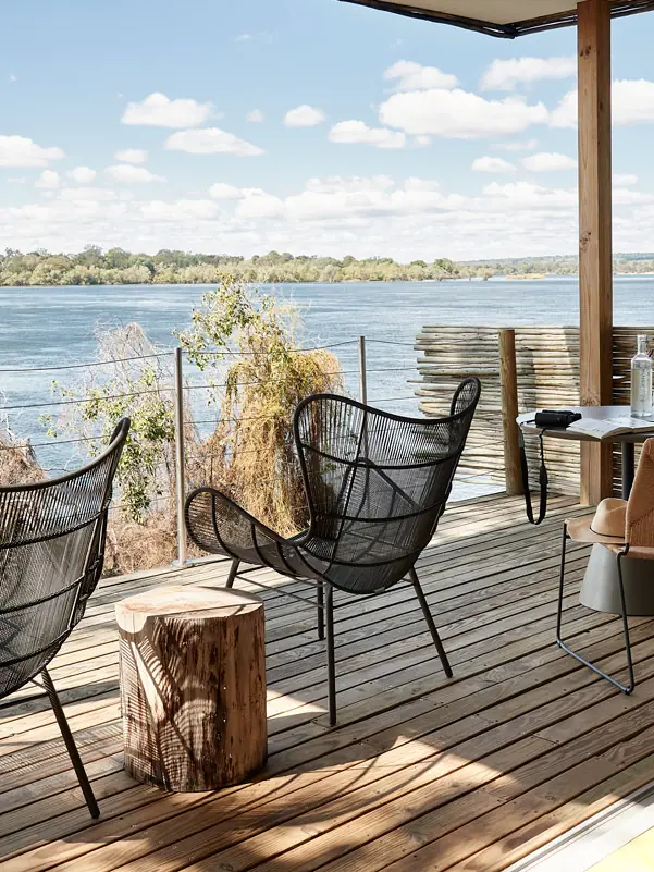 Riverside deck with seating overlooking wide waterway and trees, Island Treehouse Suites, Victoria Falls, Zimbabwe