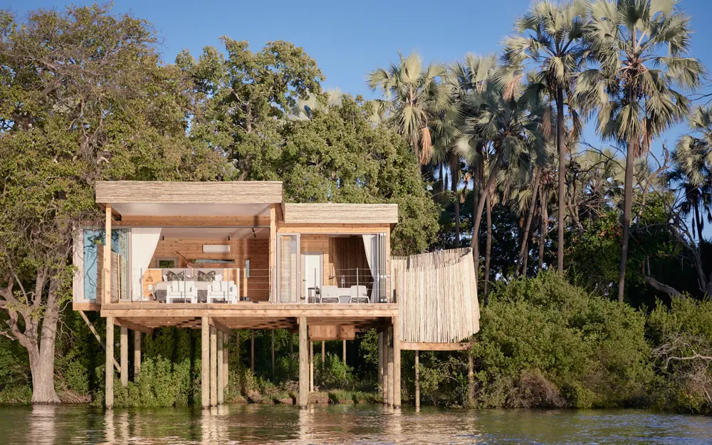 Wooden riverside lodge on stilts surrounded by vegetation, Island Treehouse Suites, Victoria Falls, Zimbabwe