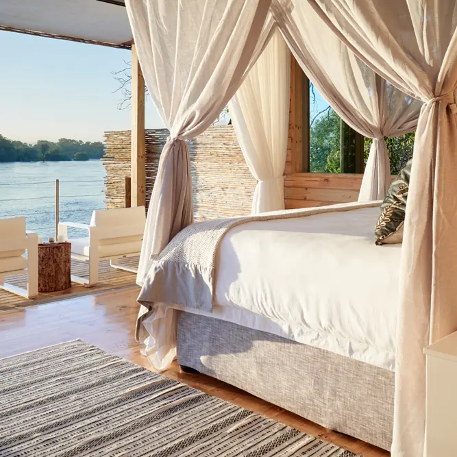 Waterfront bedroom with flowing curtains overlooking river, Island Treehouse Suites, Victoria Falls, Zimbabwe
