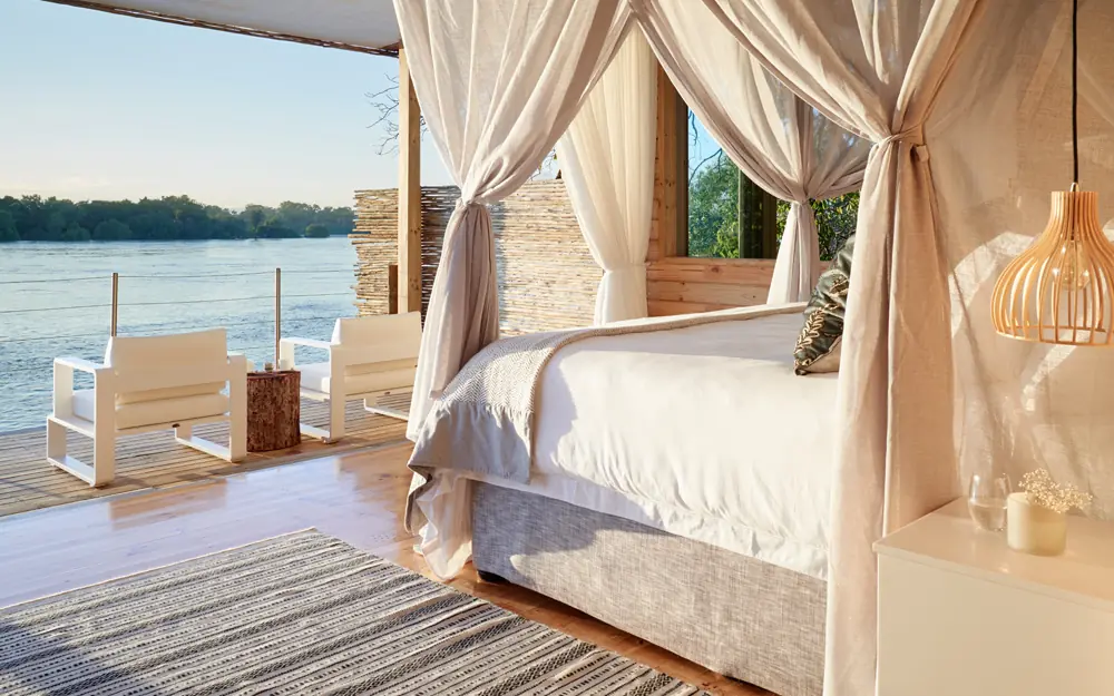 Waterfront bedroom with flowing curtains overlooking river, Island Treehouse Suites, Victoria Falls, Zimbabwe