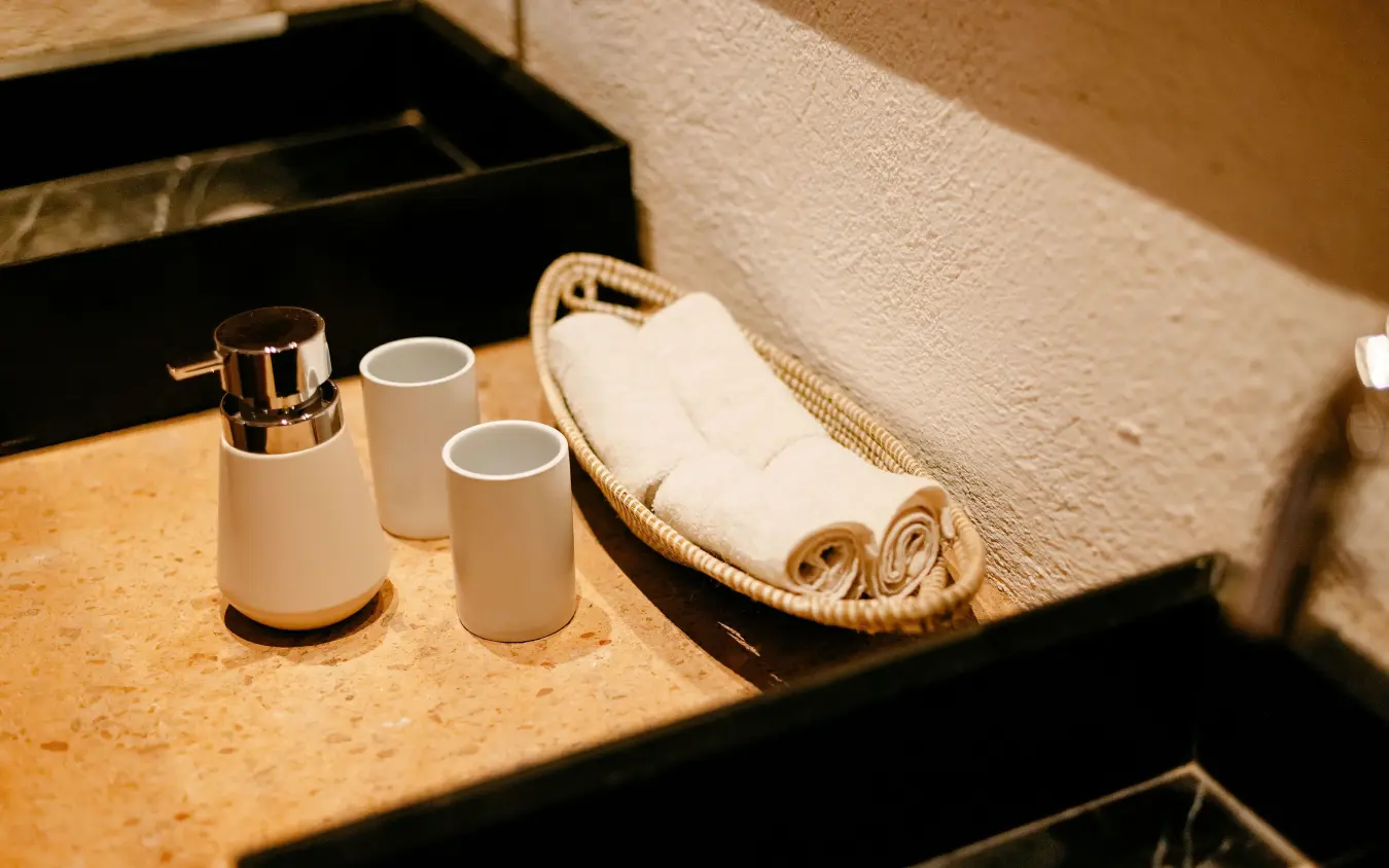 Bathroom counter with soap dispenser, cups, and rolled towels, Villa Kigali, Kigali, Rwanda