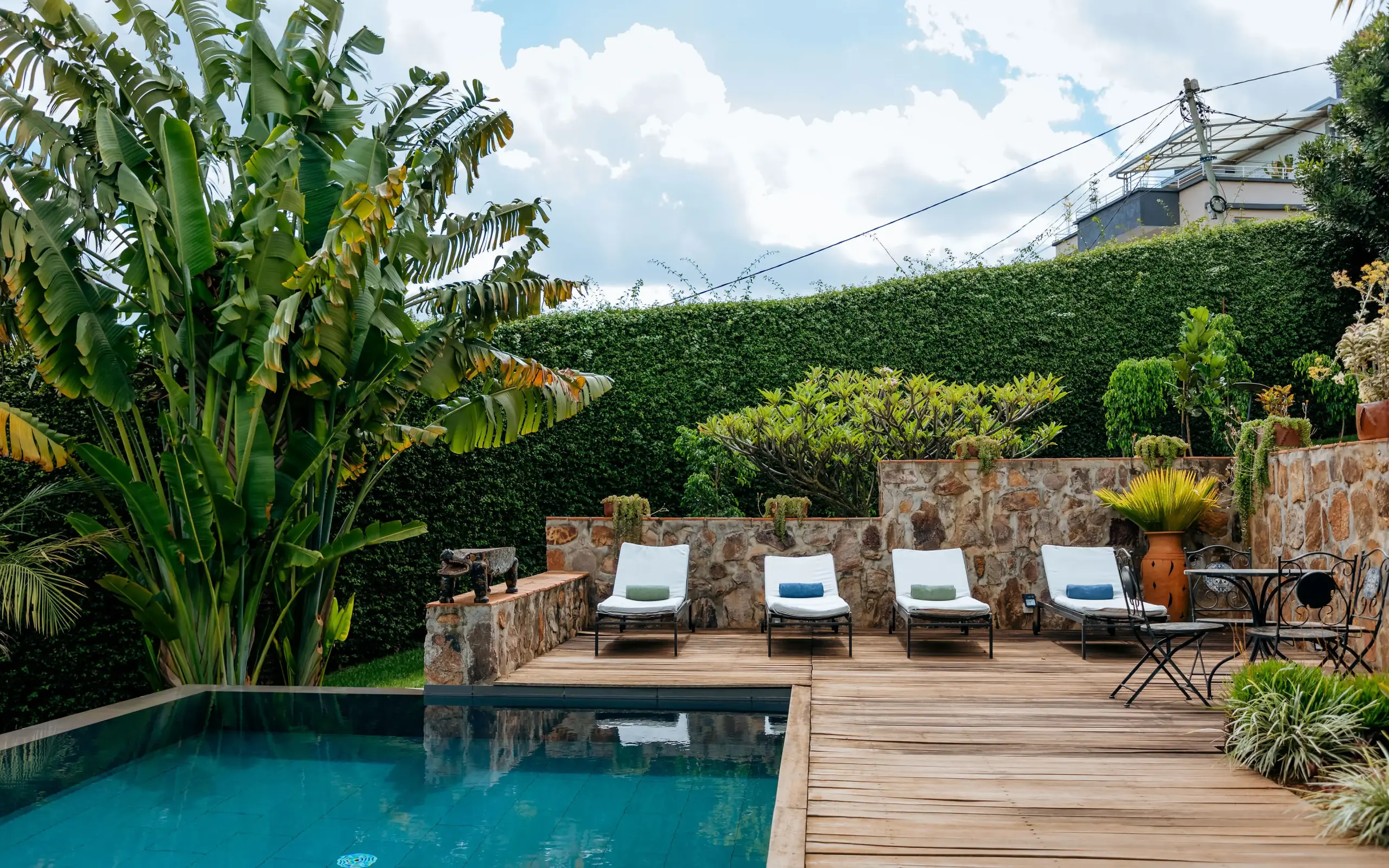 Swimming pool with loungers and stone terrace surrounded by hedges, Villa Kigali, Kigali, Rwanda
