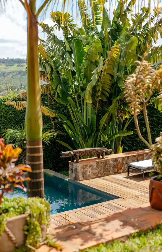Infinity pool with wooden deck and tropical plants overlooking valley, Villa Kigali, Kigali, Rwanda