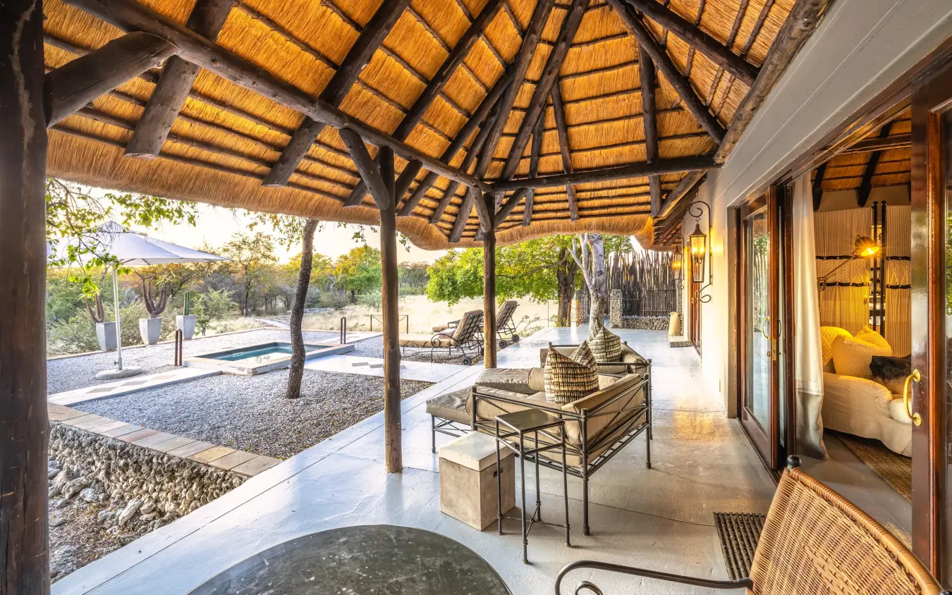 Thatched pavilion with lounge seating overlooking pool and savanna landscape, Villa Mushara, Etosha National Park, Namibia